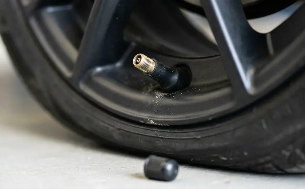 Why Do Tires Lose Pressure? 9 Real Reasons Explained 4 Close-up of a tire valve stem with a valve cap removed